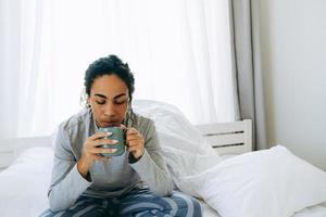 donna africana che beve caffè sul letto foto