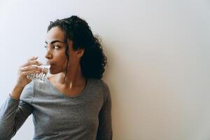 giovane donna di colore che beve acqua durante il tempo trascorso a casa foto