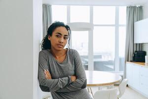 donna nera che guarda la telecamera mentre è appoggiata al muro a casa foto