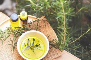 bottiglia di olio essenziale ingredienti termali naturali olio di rosmarino per aromaterapia e piante di foglie di rosmarino sullo sfondo - cosmetici biologici con estratti di erbe foto