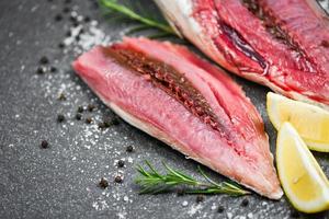 filetto di pesce fresco affettato per bistecca o insalata con erbe spezie rosmarino e limone - pesce crudo di mare su sfondo nero piatto, tonno longtail, filetto di tonno orientale ingredienti per cucinare cibo foto