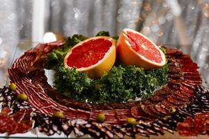 antipasto di carne. frutta fresca affettata sul tavolo celebrativo. affettare salsiccia e pompelmo foto