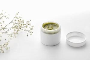 dermatologia a base di erbe igiene cosmetica crema verde con fiori. prodotto per la cura della pelle in contenitore su sfondo bianco. cosmetici per la cura della pelle, concetto di spa di bellezza, spazio di copia foto