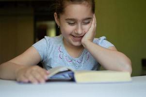 bambino che legge un libro a tavola foto