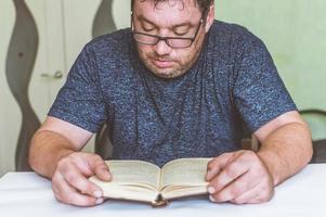 uomo che legge un libro a tavola, fa uno spuntino mentre legge, una breve pausa foto