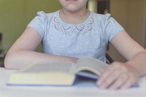 bambino che legge un libro a tavola foto