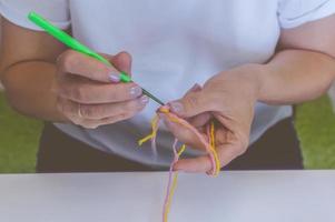 ragazza lavora a maglia con ferri da maglia e uncinetto a casa. in una maglietta bianca. maglia a mano foto