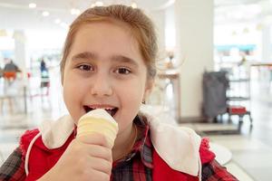 ragazza adolescente a mangiare il gelato in un cono in un centro commerciale food court. cibo malsano. foto