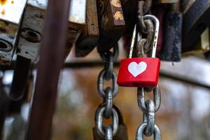 lucchetto love in metallo sul ponte, rosso con cuore bianco foto