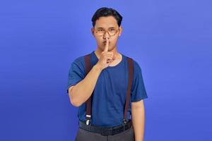uomo attraente dito sulle labbra e facendo un movimento silenzioso su sfondo viola foto