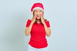 bella giovane donna con i capelli corti che porta il cappello di natale sorpreso con la bocca aperta. concetto di natale foto