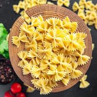 Farfalle pasta cruda fiocchi di grano duro farina sana foto