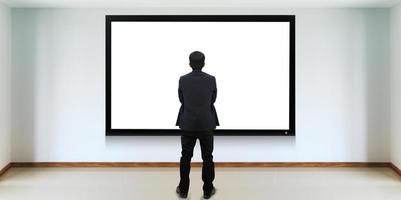 uomo d'affari di successo in piedi davanti allo schermo della tv foto