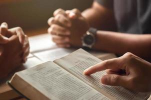 giovane che legge la Bibbia con gli amici che stanno pregando Dio si uniscono al gruppo di cellule in chiesa. un piccolo gruppo di cristiani o concetti in una chiesa in una chiesa. foto