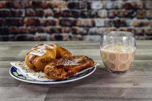 brioche con bicchiere di latte e caffè foto