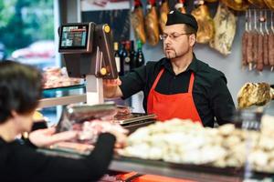 macellaio che assiste un cliente in una macelleria foto