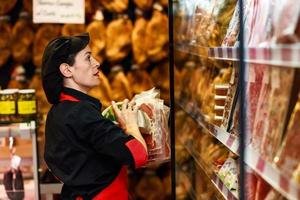 ritratto di lavoratrice che prende prodotti in macelleria foto