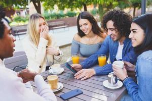 gruppo multietnico di studenti che bevono un drink sulla terrazza di un bar di strada. foto