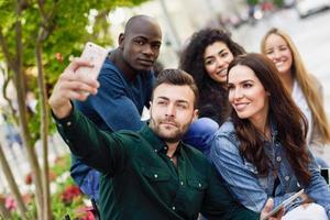 giovani multietnici che si fanno selfie insieme in un contesto urbano foto