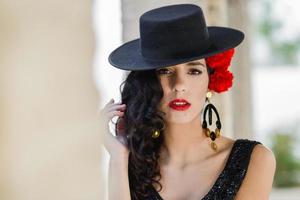 donna che indossa un cappello spagnolo e garofani rossi tra i capelli foto
