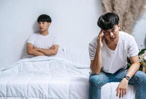 due giovani erano arrabbiati sul letto e l'altro si è seduto sul bordo del letto ed era stressato. foto