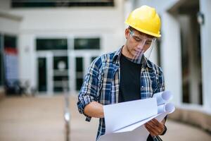 gli architetti tengono il progetto dell'edificio e controllano il lavoro. foto