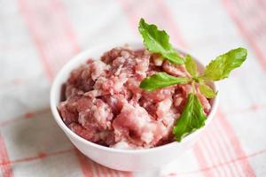 carne macinata, carne macinata o carne di maiale cruda con foglia di basilico su una ciotola di maiale macinato foto