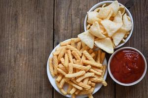 Cracker di gamberi stick sulla piastra bianca e sullo sfondo del tavolo in legno - cracker di gamberi croccanti fatti in casa o riso croccante di gamberetti e ketchup per uno spuntino tradizionale foto