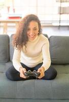 donna latina che gioca ai videogiochi con le mani che tengono il joystick foto