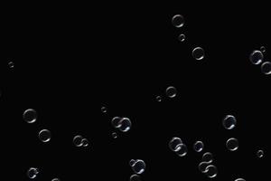 bolle trasparenti sapone modello sovrapposizione particelle astratte spruzzi d'acqua sul nero. foto