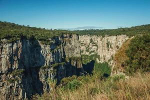 Itaimbezinho canyon con ripide scogliere rocciose che attraversa un altopiano pianeggiante coperto da foresta vicino a cambara do sul. una piccola cittadina di campagna nel sud del Brasile con incredibili attrazioni turistiche naturali. foto