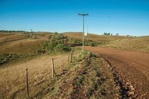 strada sterrata deserta che passa attraverso pianure rurali chiamate pampa con verdi colline e alberi vicino a cambara do sul. una piccola cittadina di campagna nel sud del Brasile con incredibili attrazioni turistiche naturali. foto