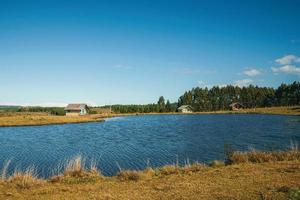 graziosi chalet in legno di fronte a un lago di acqua blu in un paesaggio collinare con alberi e cespugli secchi vicino a cambara do sul. una piccola città rurale nel sud del Brasile con incredibili attrazioni turistiche naturali. foto