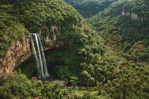 Caracol cascata che cade dalla scogliera rocciosa formando una grotta di fronte a un canyon coperto dalla foresta in un parco vicino a Canela. un'affascinante cittadina molto popolare per il suo ecoturismo nel sud del Brasile. foto