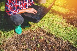 donna asiatica che utilizza tavoletta digitale nella coltivazione di ortaggi. moderna applicazione della tecnologia nell'attività di coltivazione agricola. foto