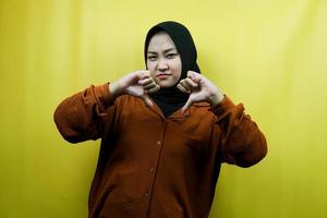 bella e allegra giovane donna musulmana asiatica con mano antipatia, pollice in giù, isolata