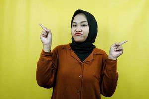 bella giovane donna musulmana asiatica con la mano che indica lo spazio vuoto che presenta qualcosa, acquolina in bocca, isolata foto