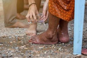 mano di versare acqua ai piedi degli anziani venerati e chiedere la benedizione felice per il festival di songkran in thailandia, tradizionale capodanno thailandese. foto