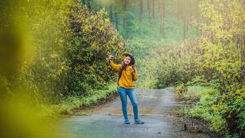 una ragazza con uno zaino sta usando il telefono per fare selfie una foto del fiore giallo bua tong. girasole messicano