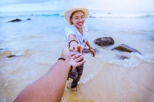 amanti asiatici felice viaggio natura sulla spiaggia. coppia che corre su una spiaggia sabbiosa. Viaggia rilassati in estate foto