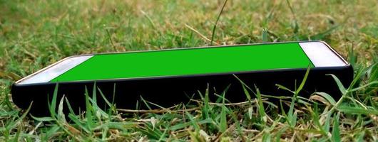 il telefono cellulare con uno schermo verde giace nell'erba foto