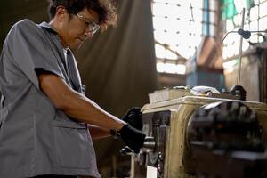 asiatico lavoratore nel produzione pianta perforazione a macchina. professionale lavoratore vicino perforazione macchina su fabbrica. finitura metallo Lavorando interno acciaio superficie su tornio macinino macchina con volante scintille. foto