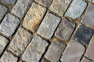 la trama della pavimentazione in pietra. sfondo di pavimentazione in ciottoli di granito. sfondo astratto di una vecchia strada di ciottoli di close-up. Mosca