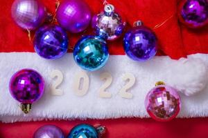 il cappello di Babbo Natale e i numeri del 2022 su sfondo rosso. foto