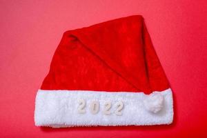 il cappello di Babbo Natale e i numeri del 2022 su sfondo rosso. foto