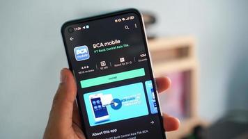 pekanbaru, indonesia 2021 - una mano che tiene un telefono cellulare apre l'applicazione della banca mobile bca. visualizzazione dell'applicazione banca mobile bca su cellulare Android. foto