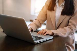 fiduciosa donna d'affari che lavora su laptop e tablet sul posto di lavoro in un ufficio moderno. foto