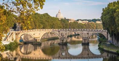 ponte sul fiume tevere a roma, italia. cupola della basilica vaticana sullo sfondo con la luce dell'alba. foto