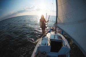 una ragazza vestita in piedi su una barca a vela foto