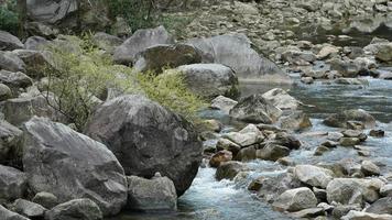 la vista del fiume con l'acqua che scorre su pietre e rocce nella valle delle montagne foto